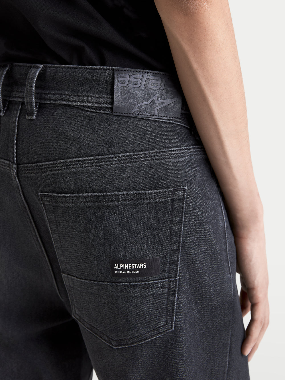 Alpinestars Flex-AST 7 Denim Pants Short, men's urban motorcycle denim pants in faded black, close-up back view showing the leather waist patch, branded back pocket label, and technical single-layer construction