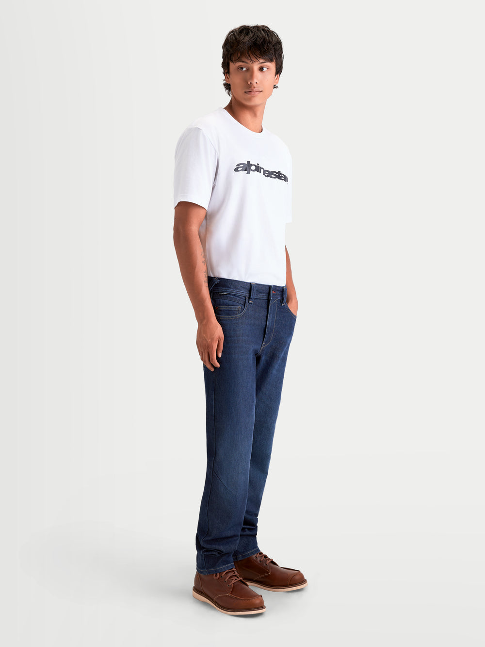 Alpinestars Flex-AST 7 Denim Pants Short, men's urban motorcycle riding jeans in dark blue, worn by a model in a white t-shirt and brown boots, featuring AA-rated single-layer protective denim and a tapered fit.