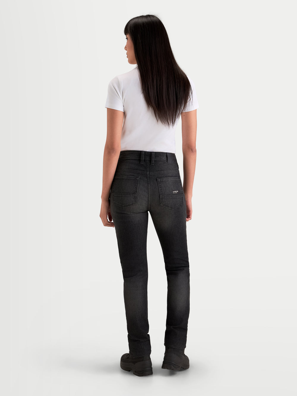 Alpinestars Stella Flex-AST 7 Denim Pants, women's urban contemporary motorcycle riding pants in faded black, rear view showing single-layer technical denim construction, back pockets, and branded back patch worn by a model.