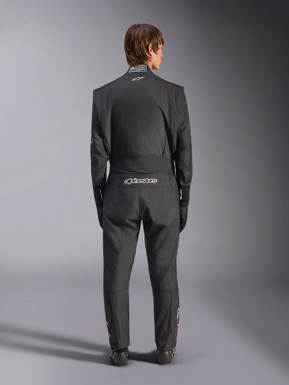 Alpinestars GP Tech V4 Suit, Auto Racing Suit, Black and White, back view featuring white Alpinestars branding and FIA certification on the collar, sleek ergonomic fit for professional driver protection