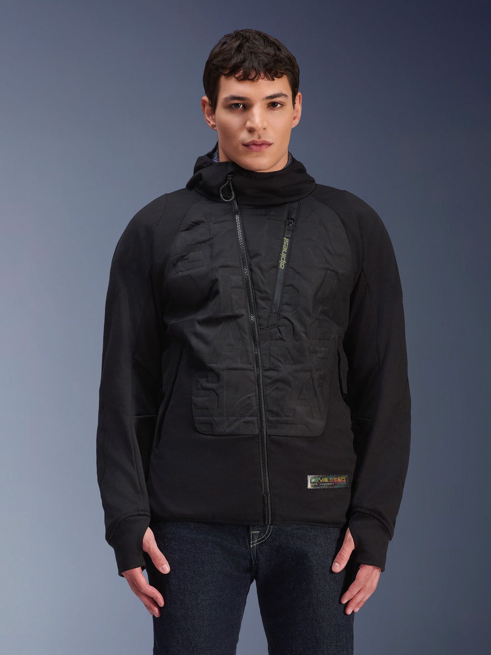 Alpinestars MO.ST.EQ Hybrid Hooded Jacket, Black urban motorcycle jacket, model wearing mid-season padded hoodie with angled front zipper, seamless padded chest panels, thumb loops, and a hood, modern streetwear-inspired riding gear