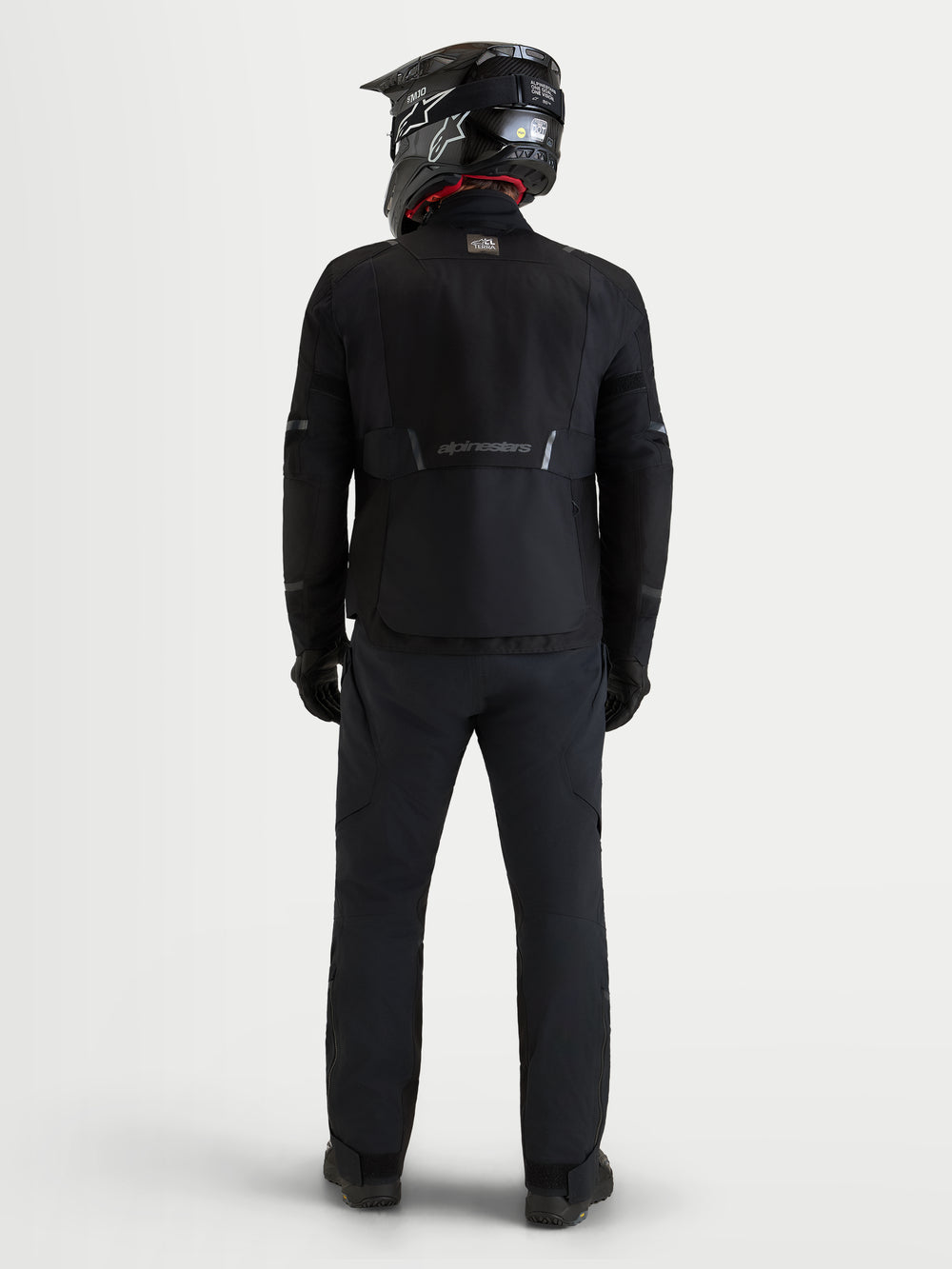 Alpinestars St-7 V2 2L Gore-Tex Jacket, men's black motorcycle adventure touring jacket, back view showing rider wearing a matching helmet and pants