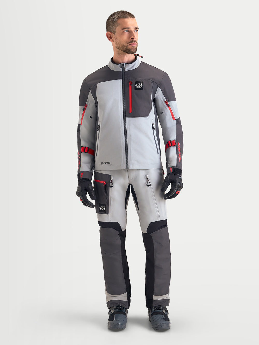 Alpinestars Arenis Gore-Tex® Jacket, men's adventure touring motorcycle jacket in mid gray, deep gray, and black, front studio view showing waterproof textile construction and red zipper details.