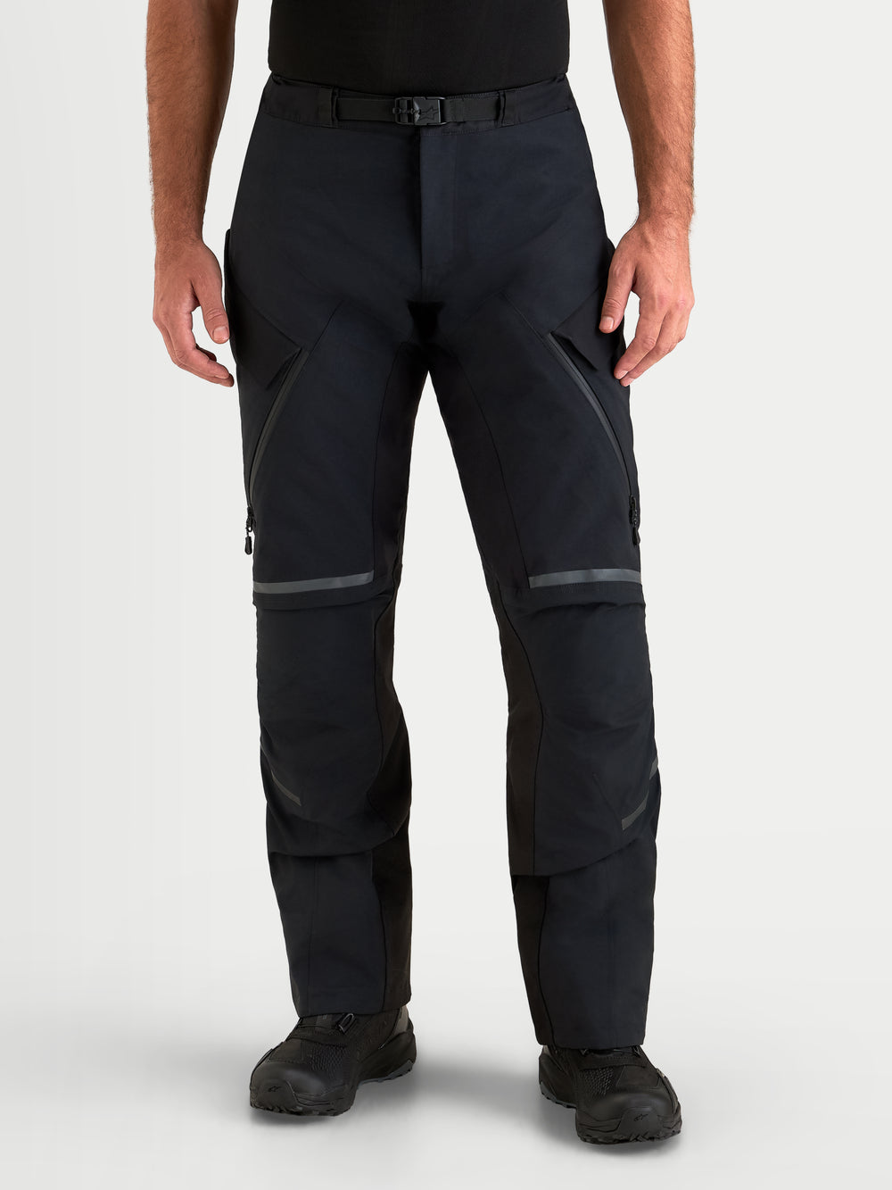 Alpinestars St-7 V2 2L Gore-Tex Pants, men's adventure touring motorcycle pants in black, front view on a model wearing waterproof textile gear with magnetic waist closure and thigh ventilation zips.