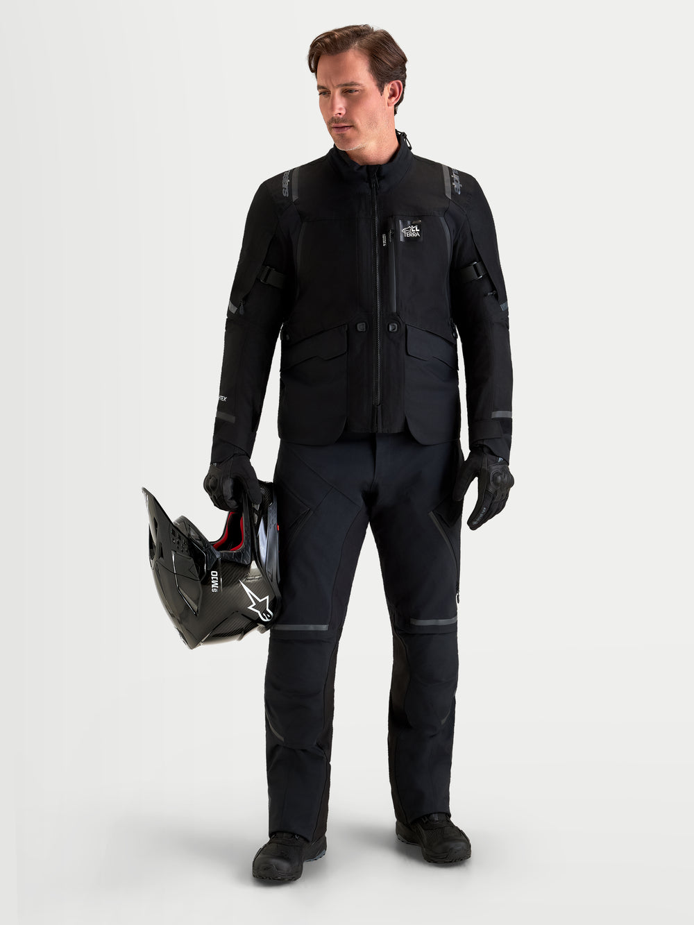 Alpinestars St-7 V2 2L Gore-Tex Pants, men's adventure touring motorcycle pants in black, front view on a model wearing matching gear and helmet, waterproof textile construction.