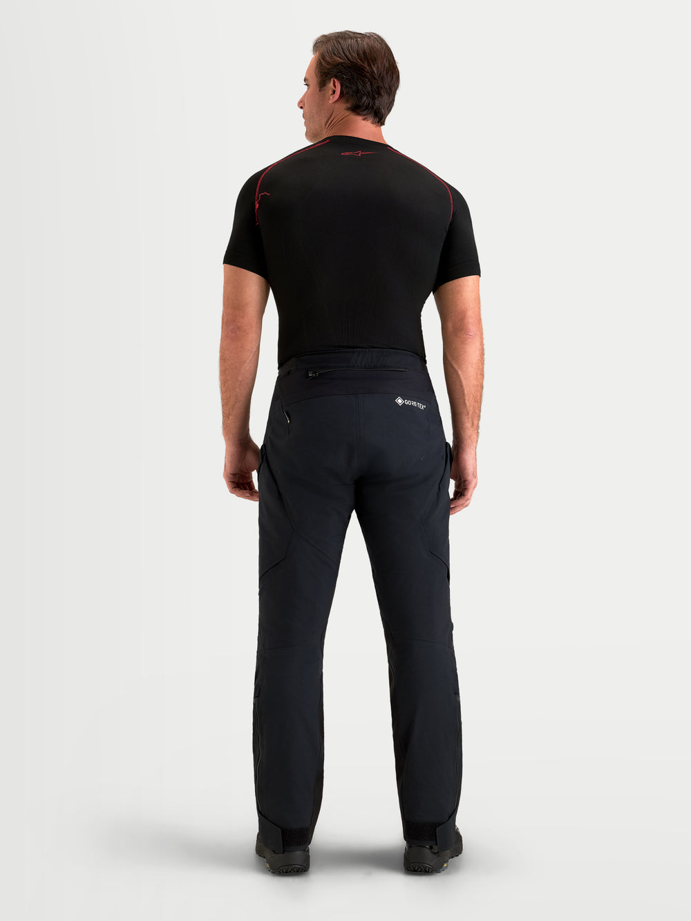 Alpinestars St-7 V2 2L Gore-Tex Pants, men's adventure touring motorcycle pants in black, rear profile view worn by a model showing waterproof textile construction, reinforced seat area, and GORE-TEX branding.