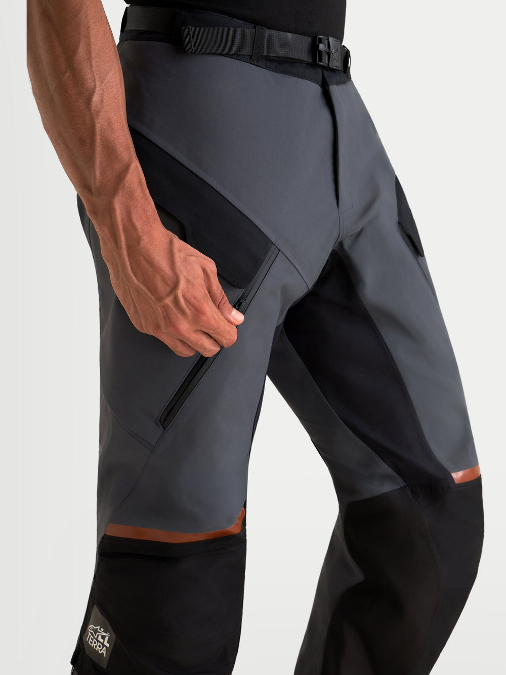 Alpinestars St-7 V2 2L Gore-Tex Pants, men's adventure touring motorcycle pants in deep gray and black, close-up view on a model unzipping the thigh ventilation pocket