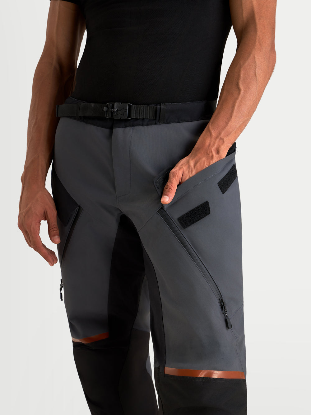 Alpinestars St-7 V2 2L Gore-Tex® Pants, men's adventure touring motorcycle pants in deep gray and black, close-up view showing the waterproof textile construction, integrated thigh ventilation zips, and magnetic waist buckle closure worn by a model.