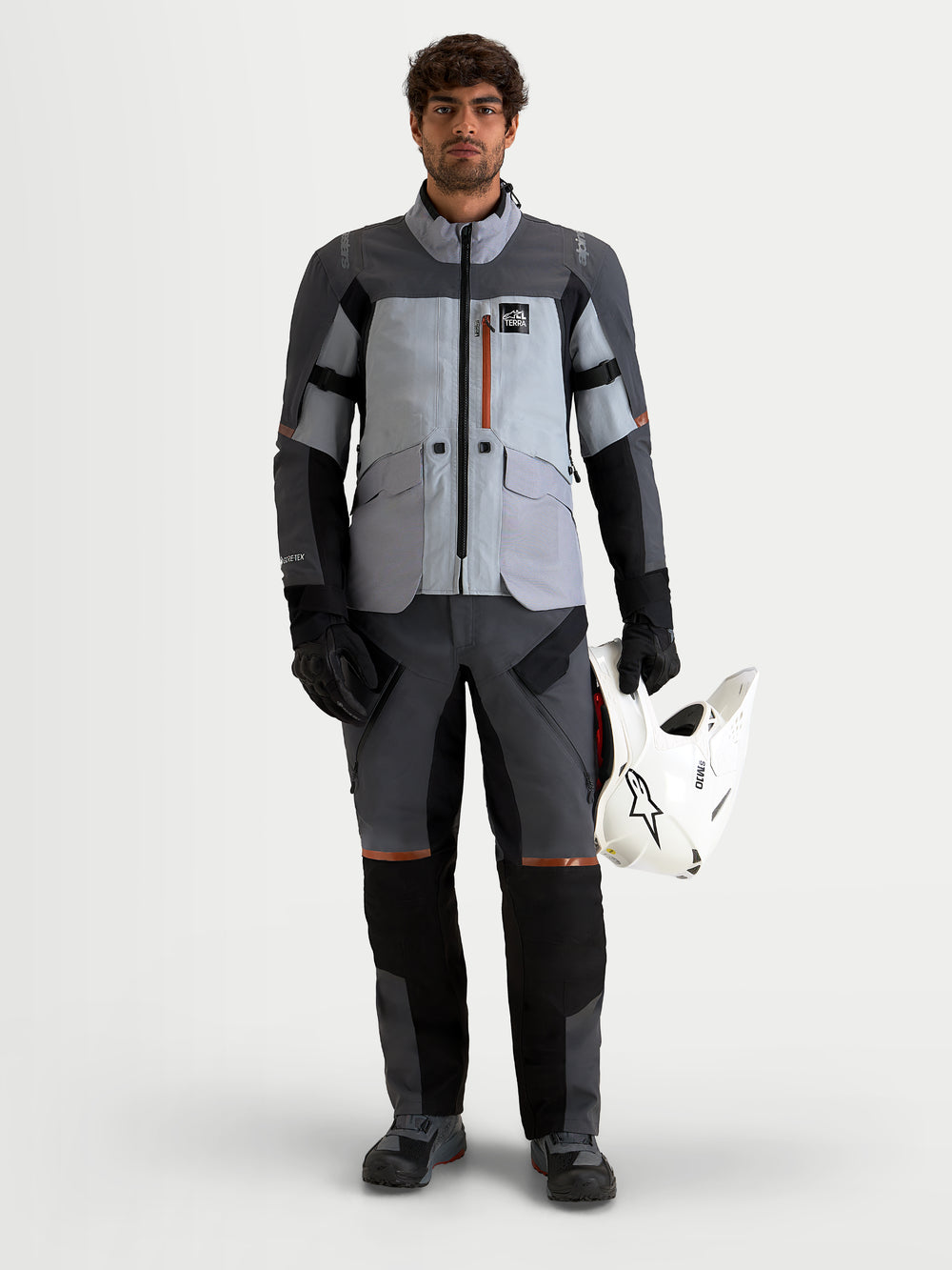 Alpinestars St-7 V2 2L Gore-Tex Pants, men's adventure touring motorcycle pants in deep gray and black, front full-length view on a model wearing matching gear and holding a helmet.