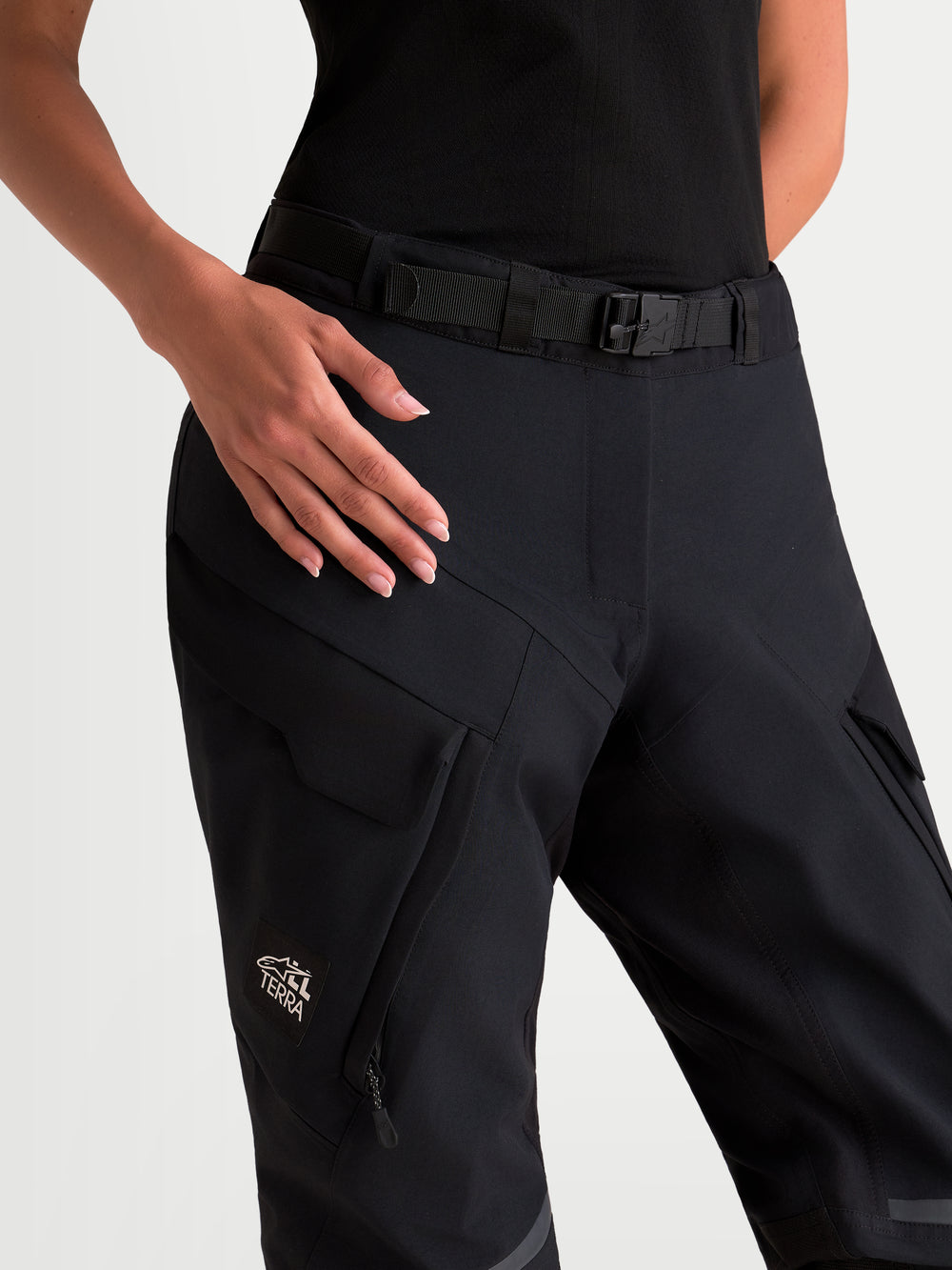 Alpinestars Stella ST-7 V2 2L Gore-Tex Pants Short, women's adventure touring motorcycle pants, black, close-up view showing magnetic-buckle waist closure, cargo pockets, and All Terra branding worn by a model