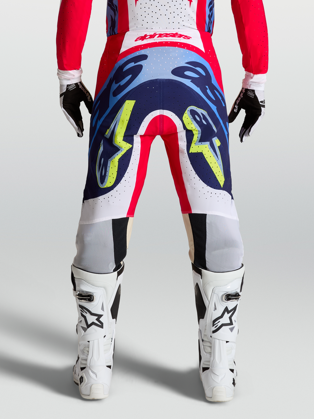 Rear view of Alpinestars Supertech Dyna Pants in fire red, white, and navy blue, showing durable motocross racing construction.