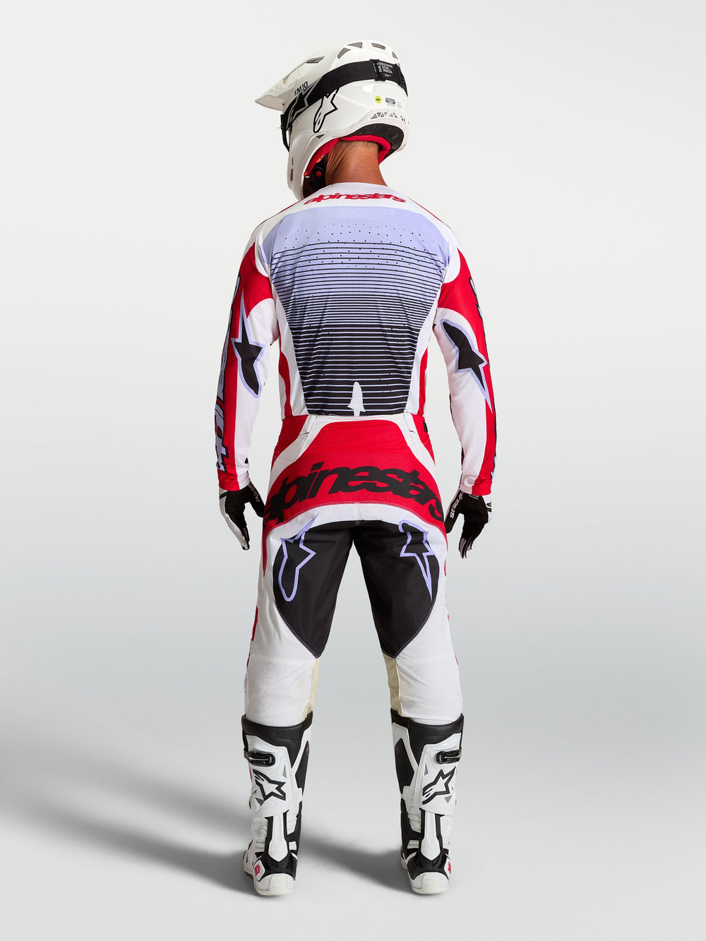 Alpinestars Techstar Maven motocross pants in Fire Red and White, rear view on a rider showing athletic race fit.