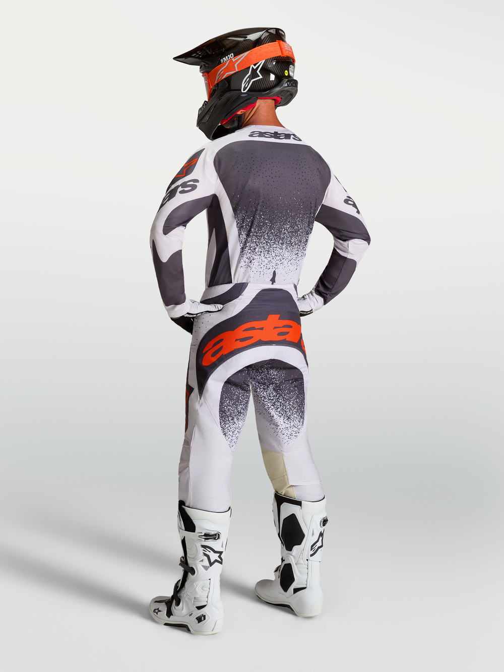 Alpinestars Techstar Swan Pants and Jersey, men's motocross gear in gray and white with red fluo accents, rear view on model.
