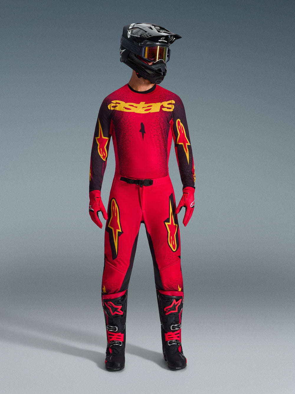 Alpinestars 2026 Supertech Scenz Pants, Motocross Pants, Red Black and Yellow, worn by a rider in a complete racing gear set, matching red and black jersey with yellow logos, black helmet, red gloves, and black boots, athletic pro-fit design for off-road competition