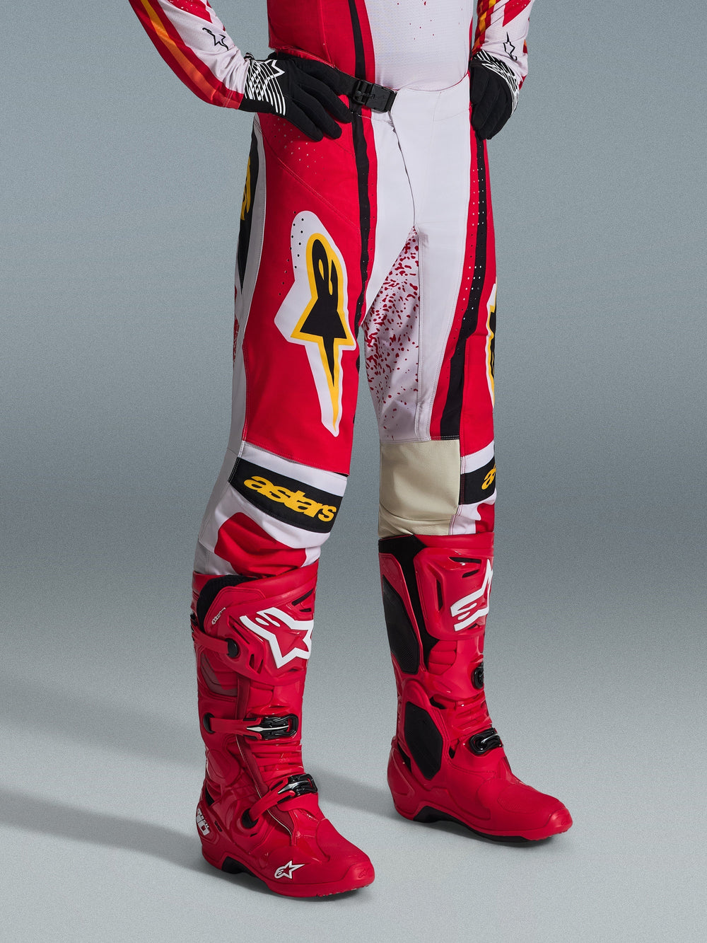 Alpinestars 2026 Techstar Nomur Pants, Motocross Pants, Red White and Black with yellow accents, worn with matching red motocross boots and black gloves, featuring yellow Alpinestars logo and 