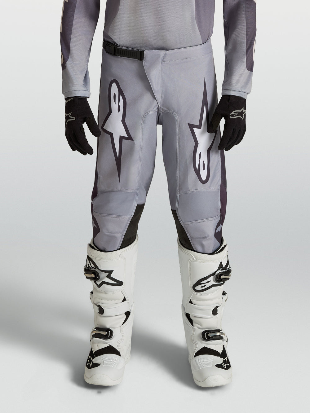 Alpinestars Youth Fluid Amber Pants, durable grey and black motocross pants for young riders in an off-road setting.