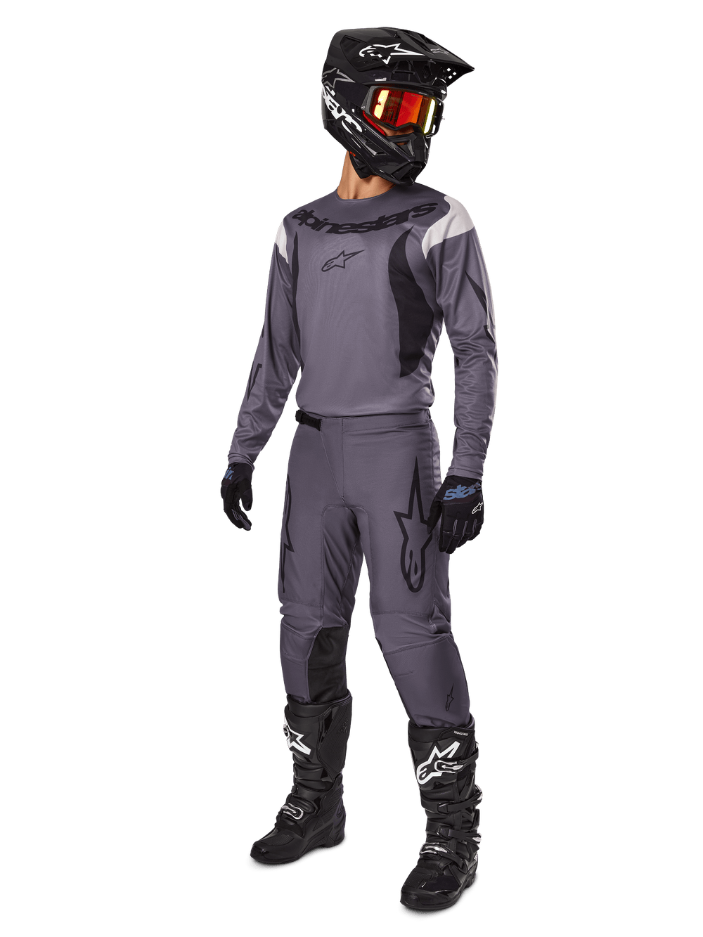Motocross rider wearing Alpinestars 2025 Fluid Haul Gear Set in Gray, including gray jersey and pants with black accents, black helmet with reddish goggles, black gloves, and black boots with white logos, complete off-road racing outfit