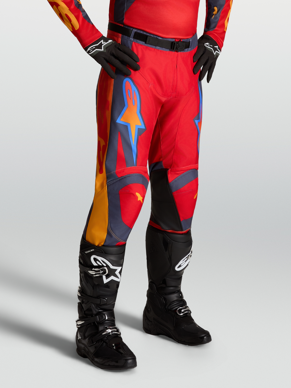 Alpinestars Racer Hunt Pants, red motocross pants for men with graystone and coral accents, on-model with black boots.