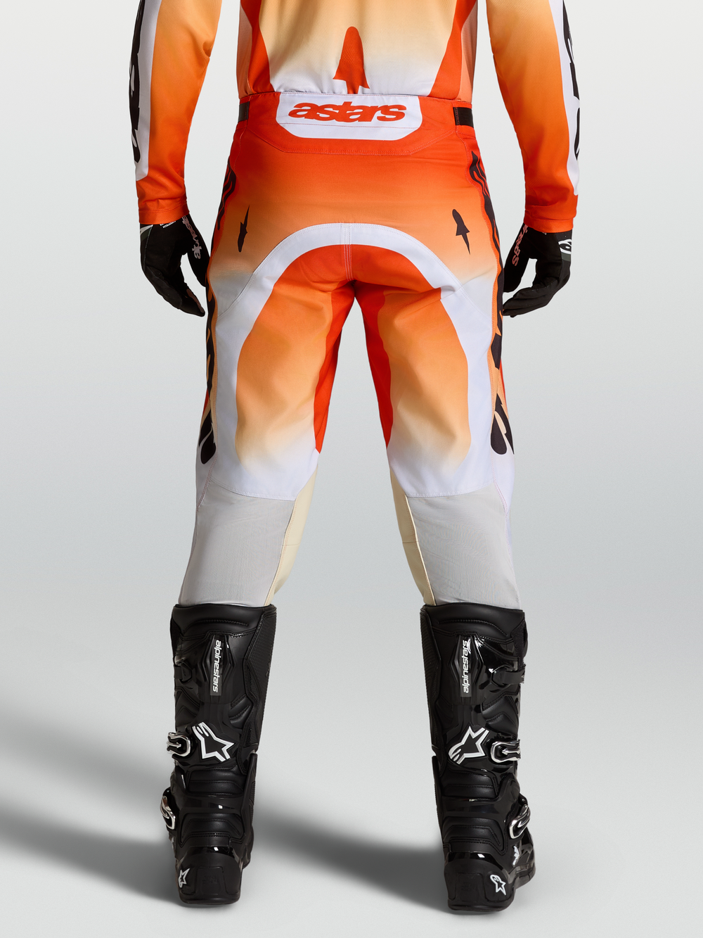 Alpinestars Racer Amber Pants, red and white motocross pants shown from the rear on-model with black boots.