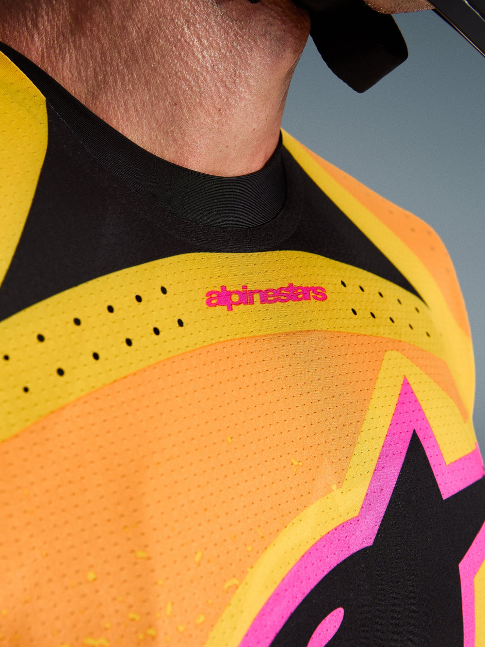 Alpinestars 2026 Techstar Nomur Jersey, Motocross Jersey, Orange Yellow Pink, close-up detail of the chest and collar, featuring laser-cut ventilation, pink branding, and breathable mesh fabric