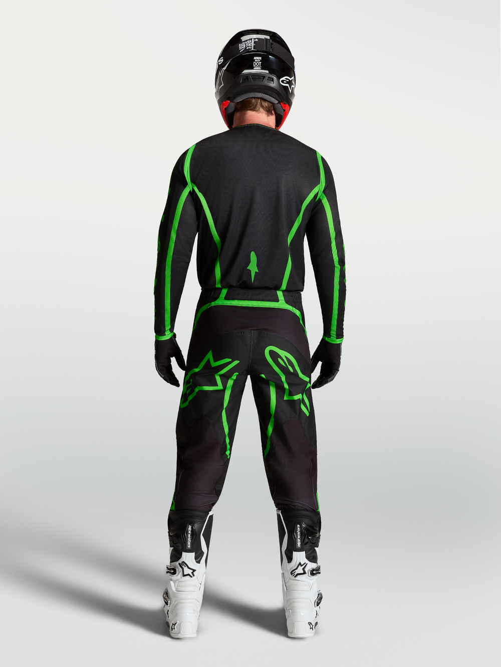 Alpinestars Fluid Apex V2 Pants, Black and Green Fluo motocross gear shown from behind on a rider with white boots.