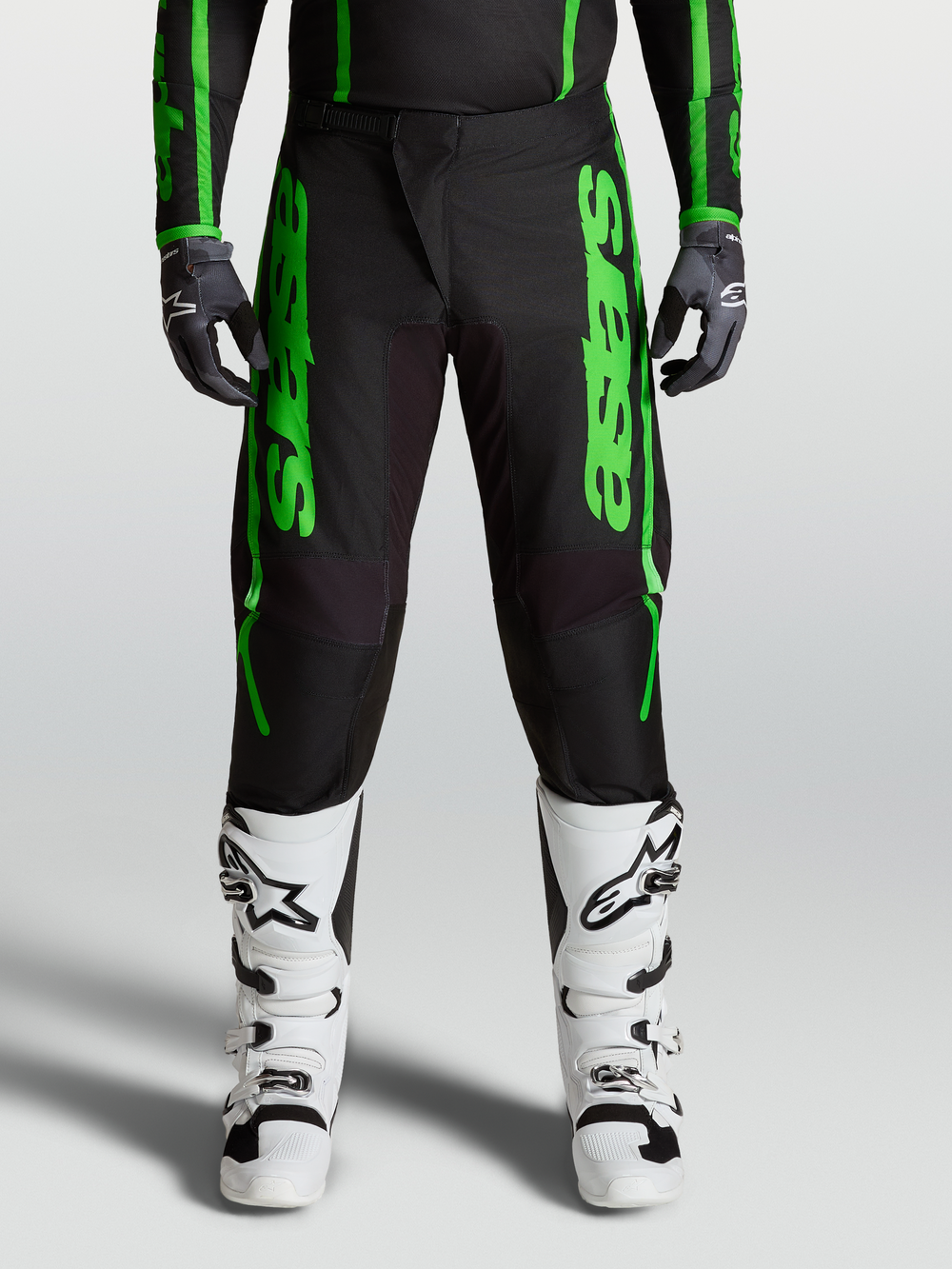 Alpinestars Fluid Apex V2 Pants, green and black motocross performance pants with reinforced knees and matching white boots.