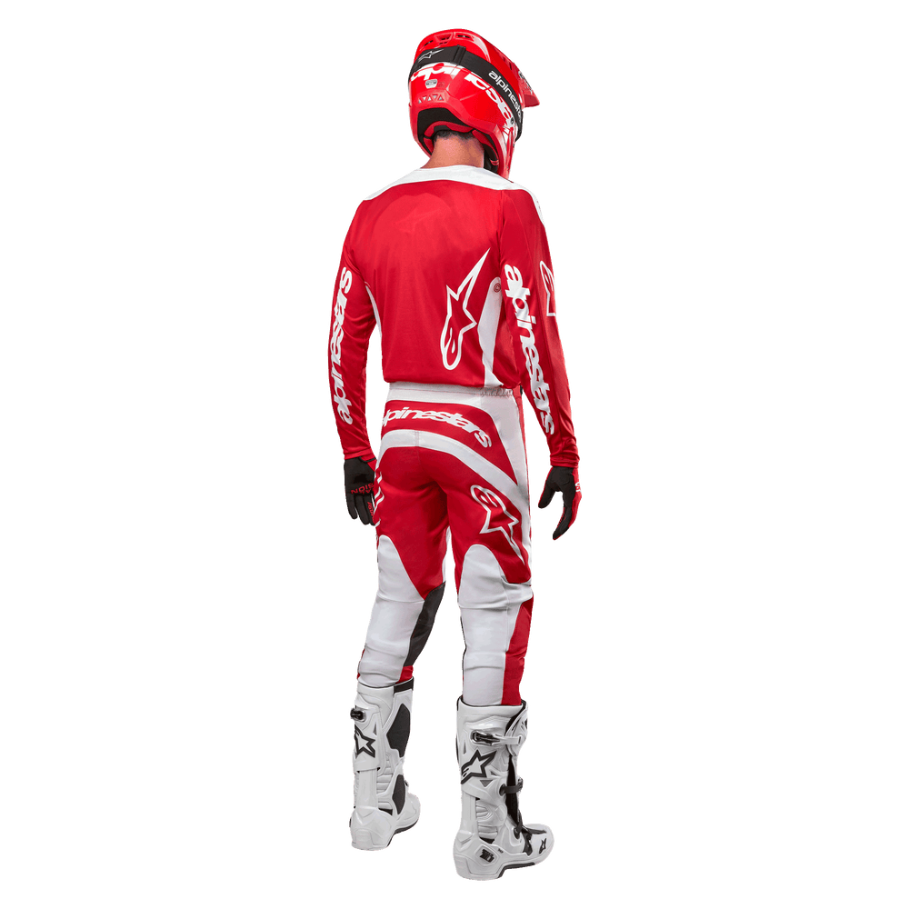 Rear view of a motocross rider wearing the Alpinestars 2024 Fluid Lurv Jersey in Mars Red White, paired with matching red and white pants, white off-road boots, and a red helmet, showing the jersey's back design and Alpinestars branding.