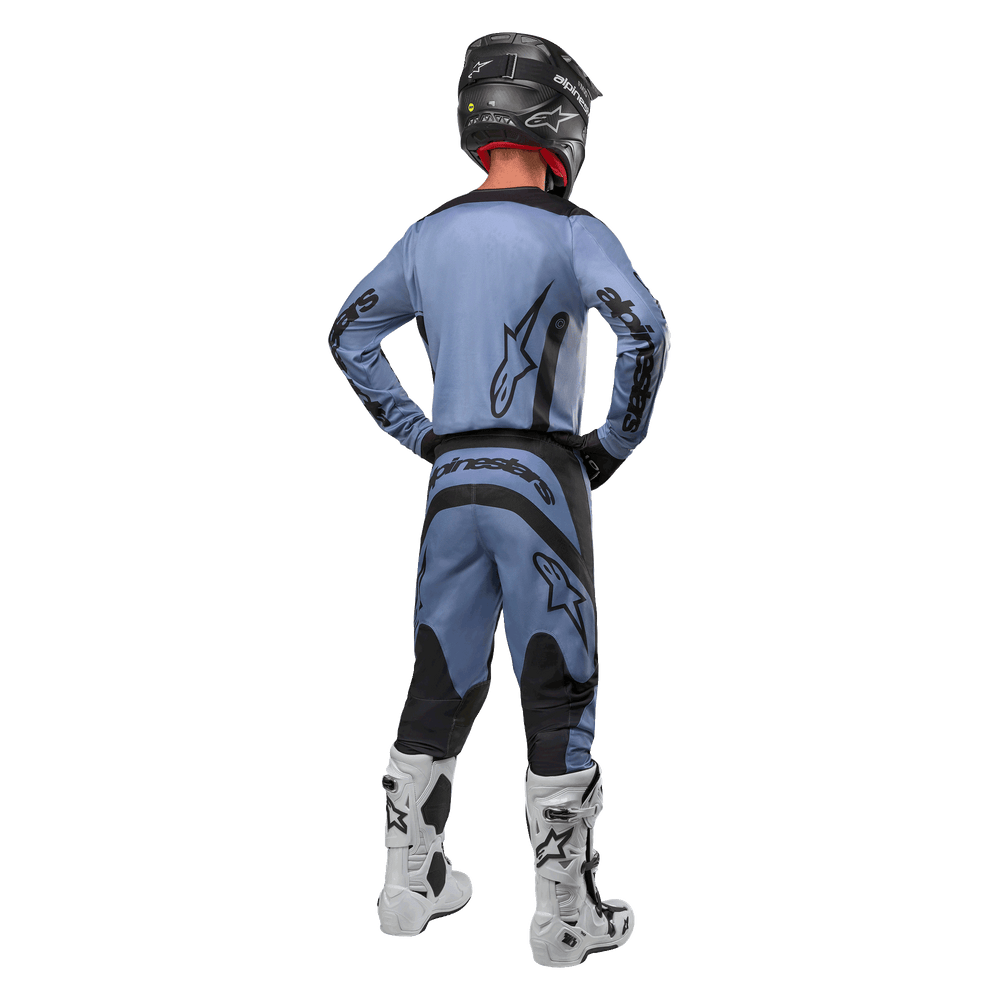 Motocross rider from behind wearing the Alpinestars 2024 Fluid Lurv Jersey and matching pants in Light Blue and Black, featuring black branding on the back and sleeves, paired with a black helmet and white boots.