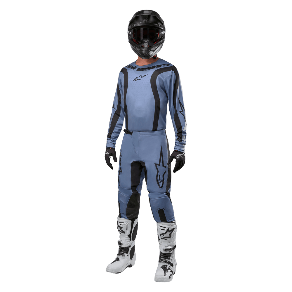 Motocross rider wearing complete racing gear, Alpinestars 2024 Fluid Lurv Jersey in light blue and black, matching light blue pants with black panels, white and black boots, black gloves, and black helmet with goggles, coordinated outfit for off-road racing
