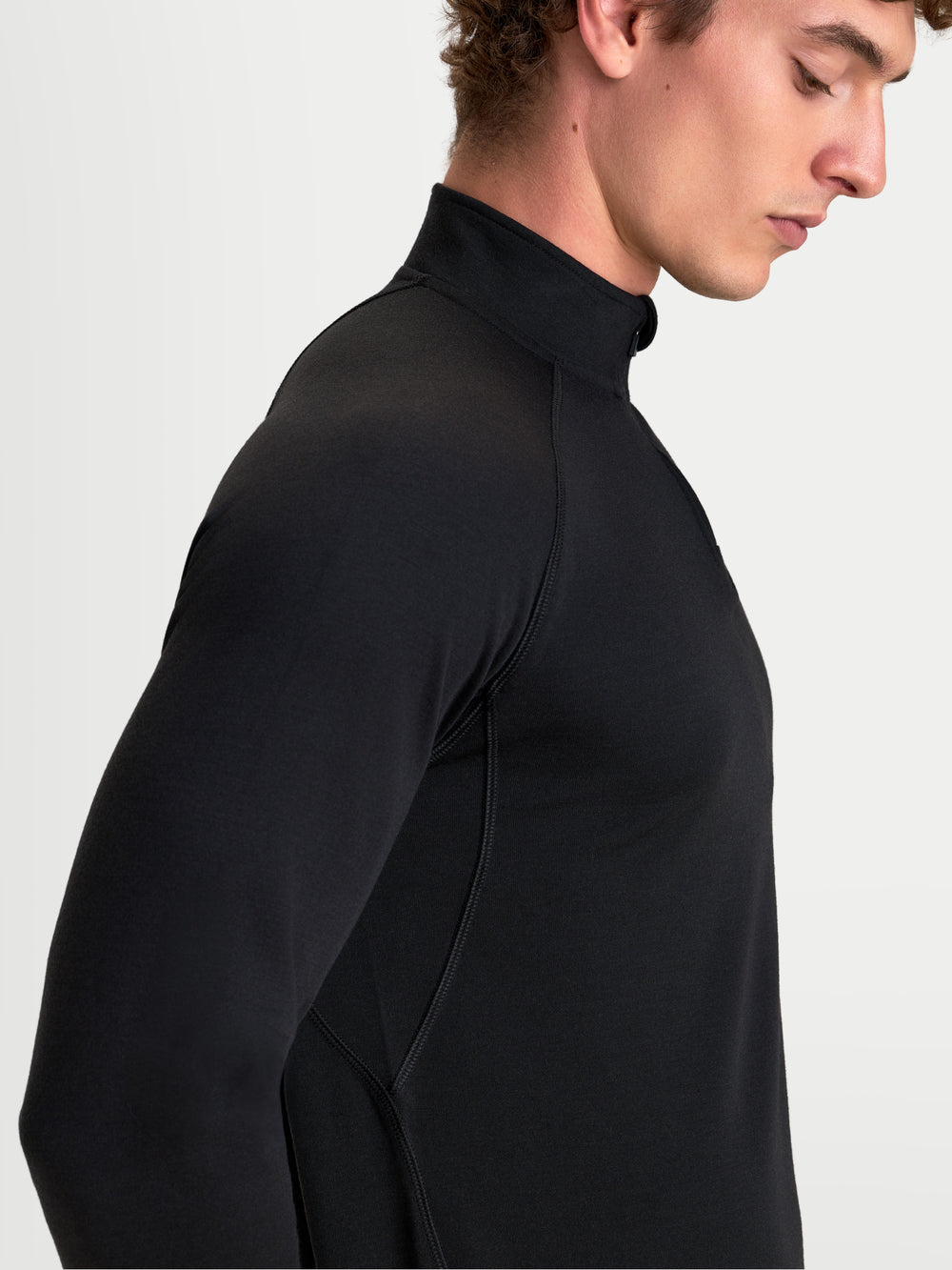 Alpinestars AT-8 Merino Top Layer, men's adventure touring long sleeve base layer in black, side profile view on a model showing merino wool thermal construction, raglan sleeves, and streamlined collar.