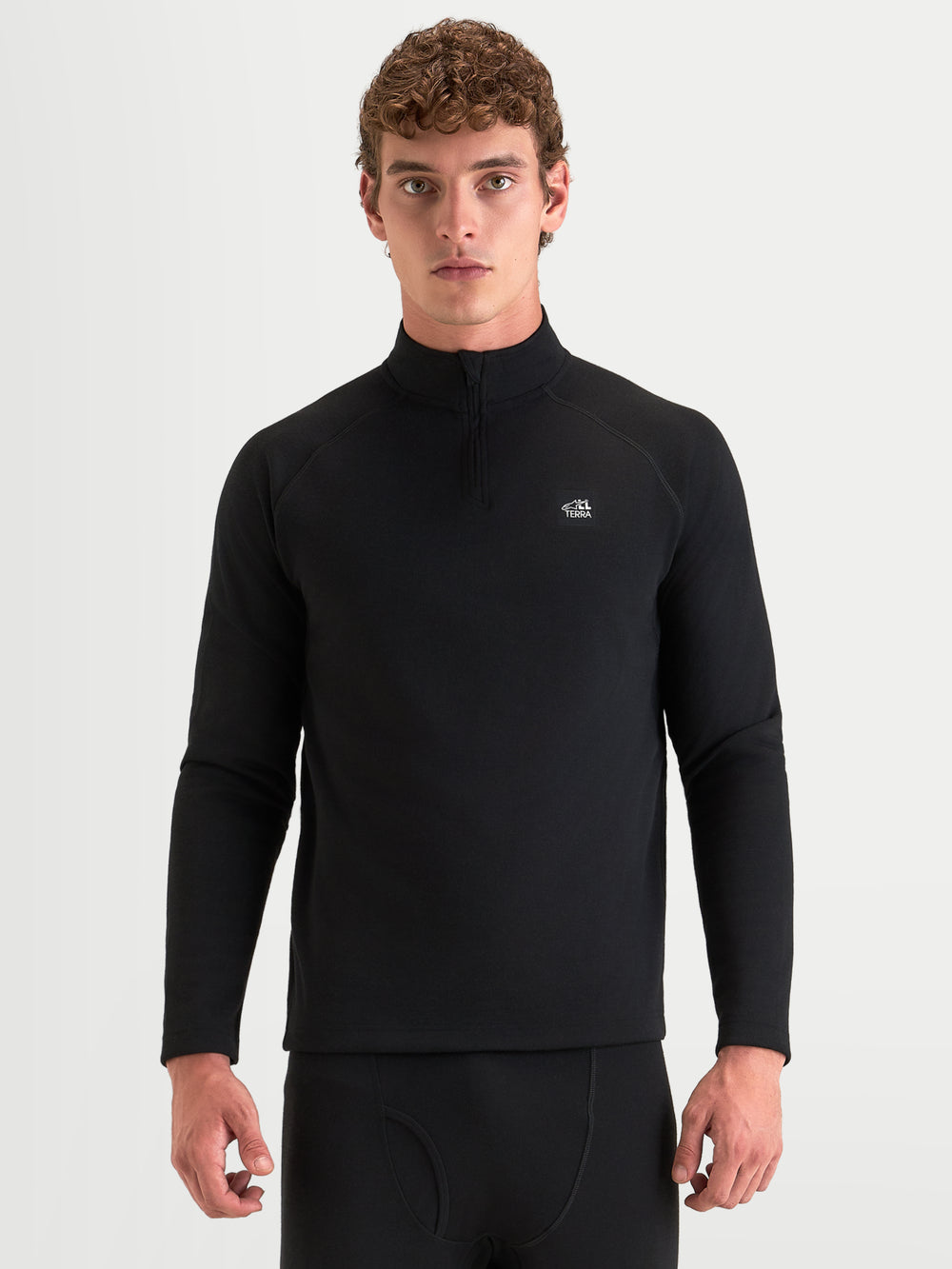 Alpinestars AT-8 Merino Top Layer, men's adventure motorcycle base layer in black, front view worn by a model showcasing long sleeves, mock neck with half-zip, and dual-layer Merino wool thermal construction.