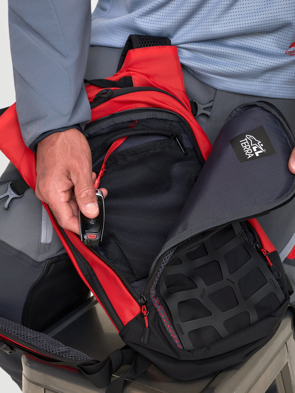 Alpinestars AT-9 Back Pack, motocross backpack in red and black, close-up view showing organized storage compartments and zip closure worn by a model.