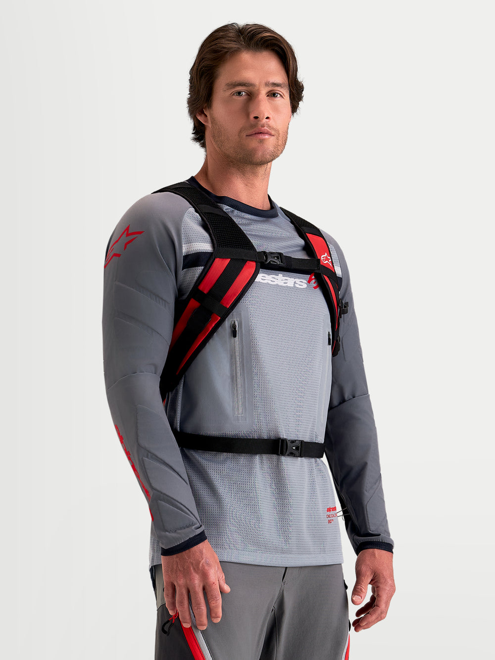 Alpinestars AT-9 Backpack, motocross backpack in black and bright red, worn by a model showcasing the padded harness and secure closure system