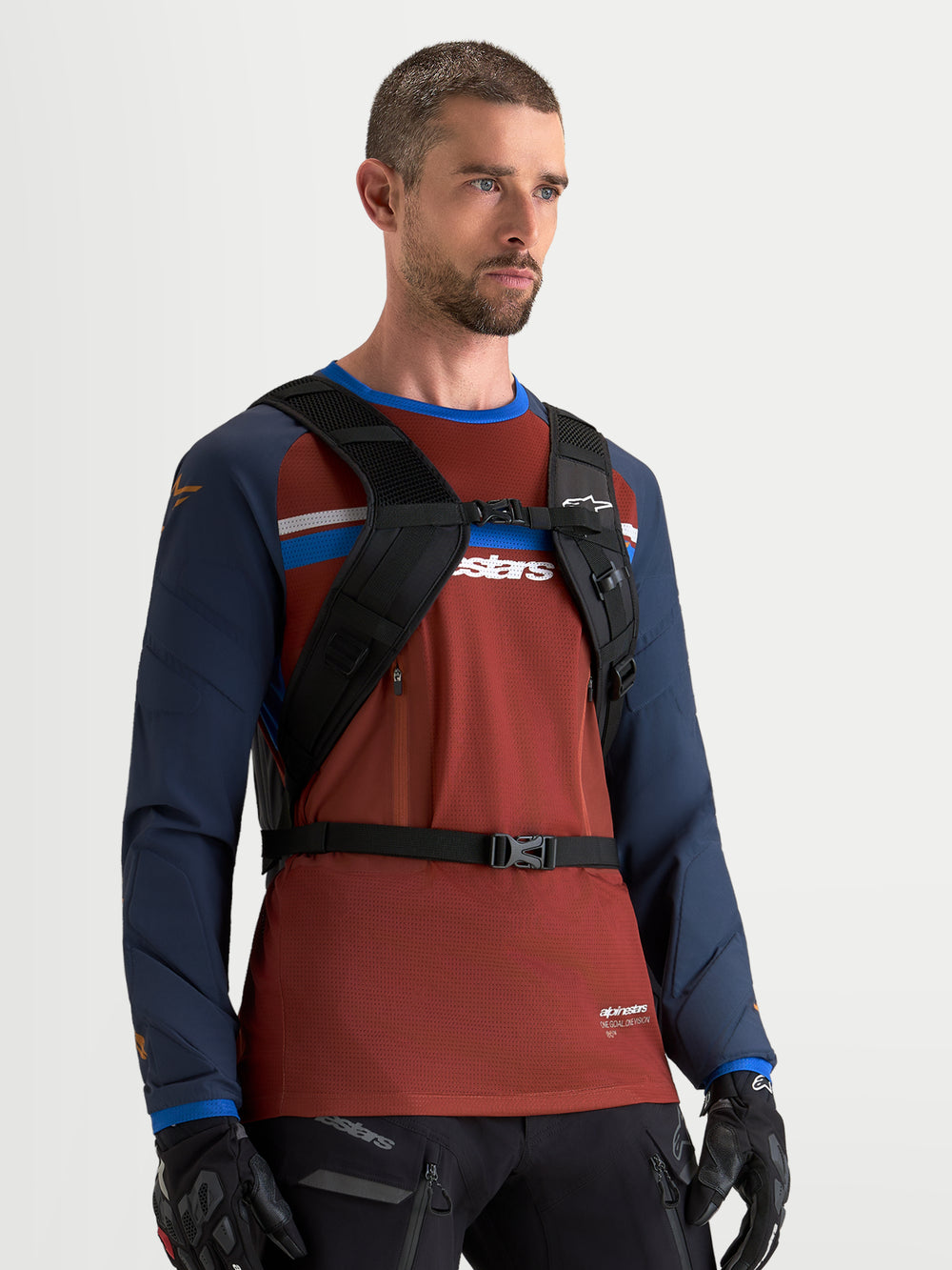 Alpinestars AT-9 Backpack, motocross backpack in black, worn by a male model showing the padded shoulder harness and chest strap system