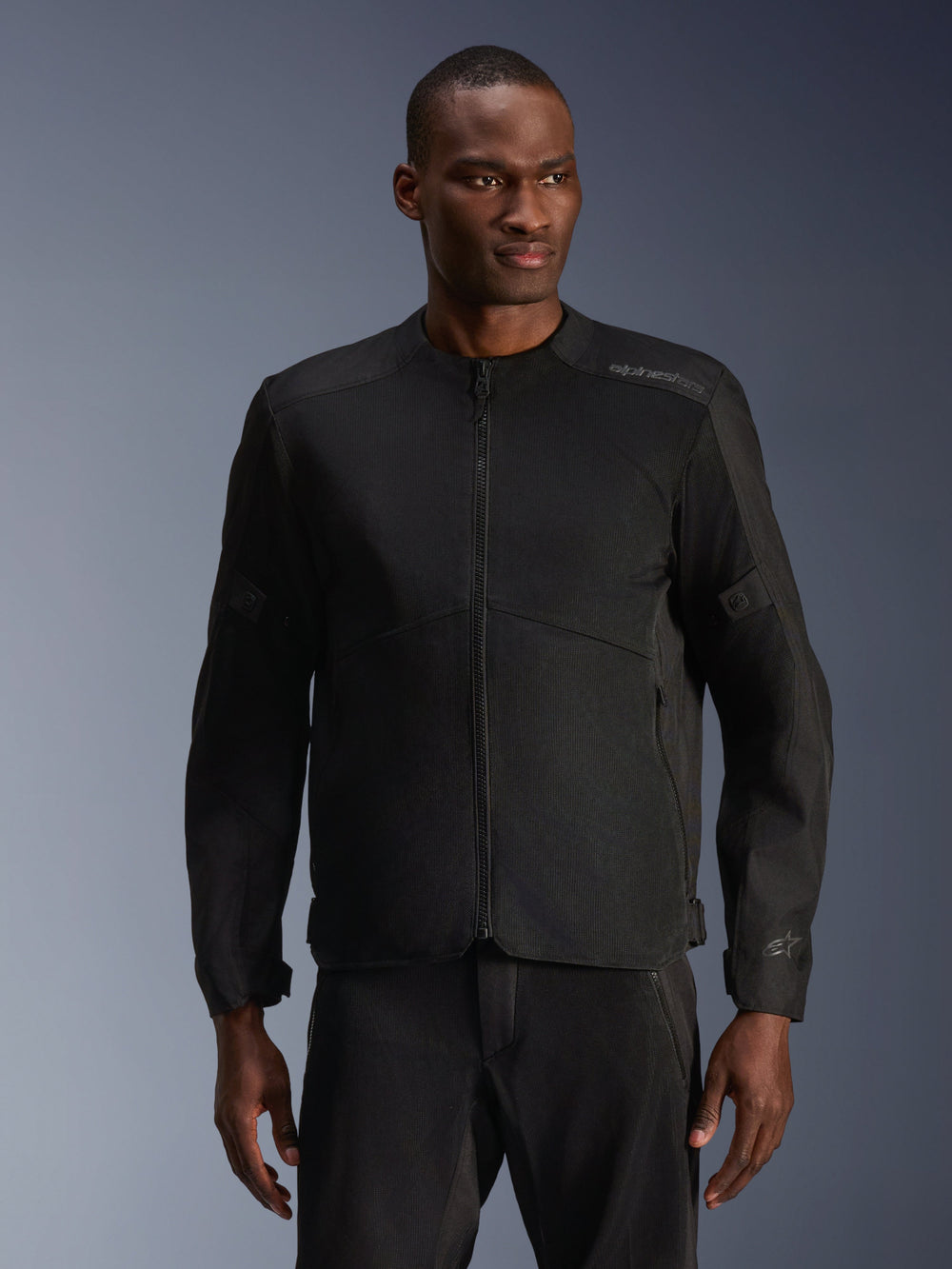 Male model wearing Alpinestars C-1 Air Jacket in Black, contemporary motorcycle jacket with extensive tech mesh panels and a full front zipper, paired with matching black riding pants, urban lifestyle and commuting aesthetic